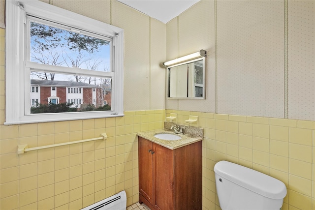 bathroom with toilet, wallpapered walls, and wainscoting