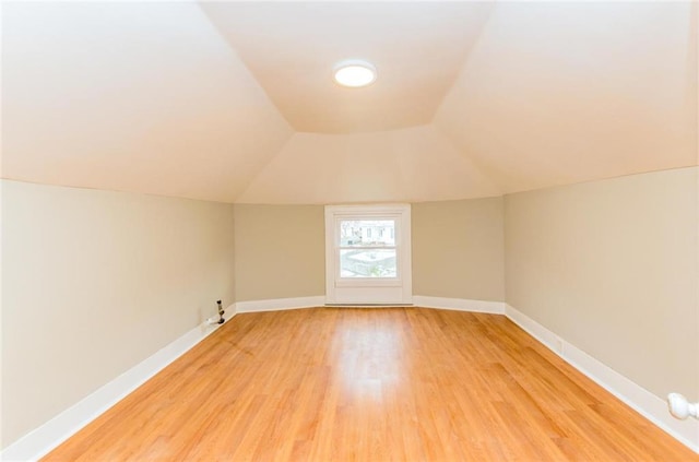 bonus room featuring light wood-type flooring, lofted ceiling, and baseboards