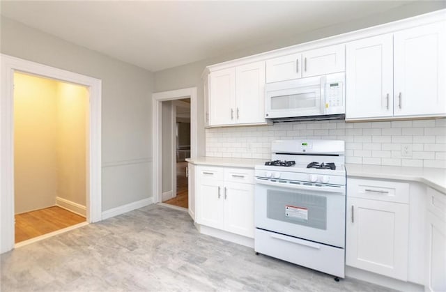 kitchen featuring light countertops, white appliances, backsplash, and white cabinetry