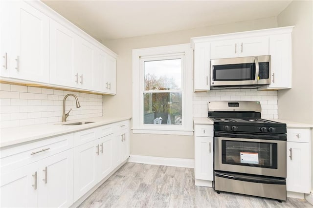 kitchen featuring appliances with stainless steel finishes, light countertops, a sink, and white cabinetry