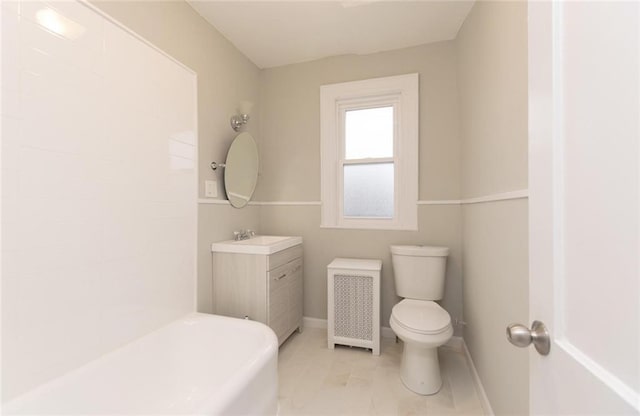 bathroom featuring toilet, vanity, baseboards, radiator, and a bathtub