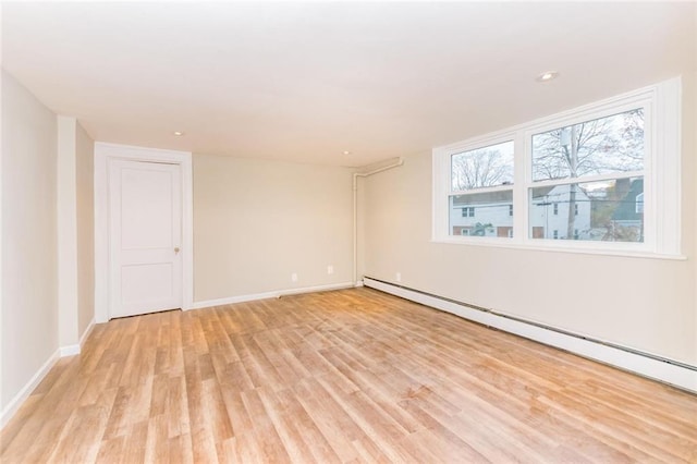 spare room featuring light wood-style flooring, a baseboard heating unit, baseboards, and recessed lighting