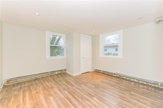 empty room with recessed lighting, a baseboard radiator, and wood finished floors