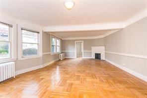 unfurnished living room featuring radiator, baseboards, a fireplace, and radiator heating unit