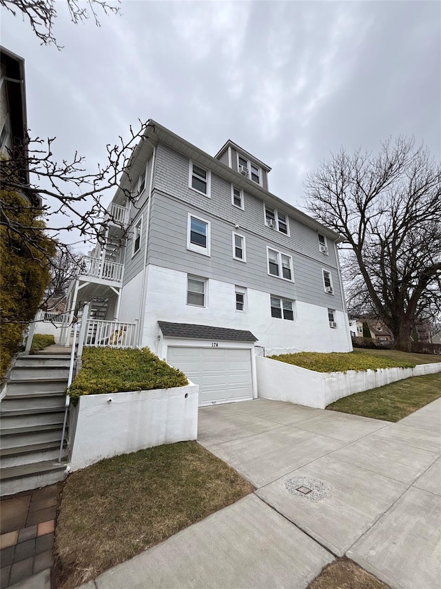 view of side of property with a garage, driveway, and stairs