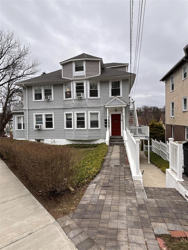 american foursquare style home with roof with shingles and fence