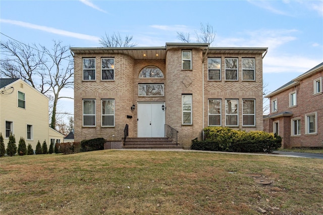 view of front facade with brick siding and a front lawn