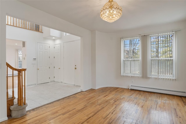 foyer featuring baseboards, a chandelier, hardwood / wood-style flooring, stairs, and a baseboard heating unit