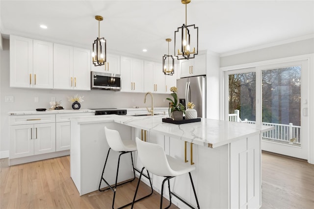 kitchen featuring light wood-type flooring, a kitchen island with sink, appliances with stainless steel finishes, and a sink