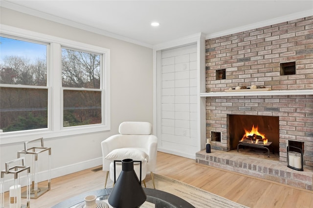 living area featuring recessed lighting, a fireplace, wood finished floors, baseboards, and crown molding