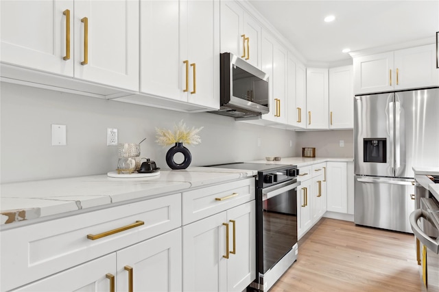 kitchen with stainless steel appliances, white cabinetry, and light stone counters