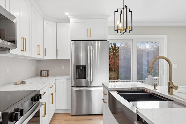 kitchen with white cabinets, light stone counters, stainless steel appliances, and decorative light fixtures