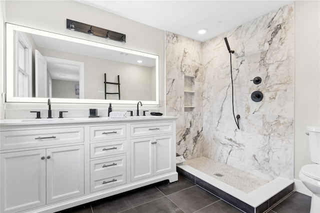 full bathroom with double vanity, a marble finish shower, a sink, and toilet