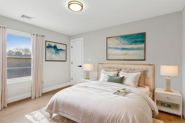 bedroom featuring baseboards, visible vents, and light wood finished floors