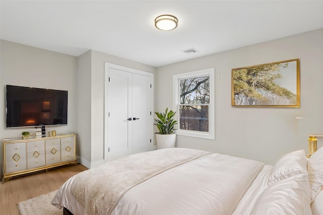 bedroom featuring a closet, wood finished floors, visible vents, and baseboards