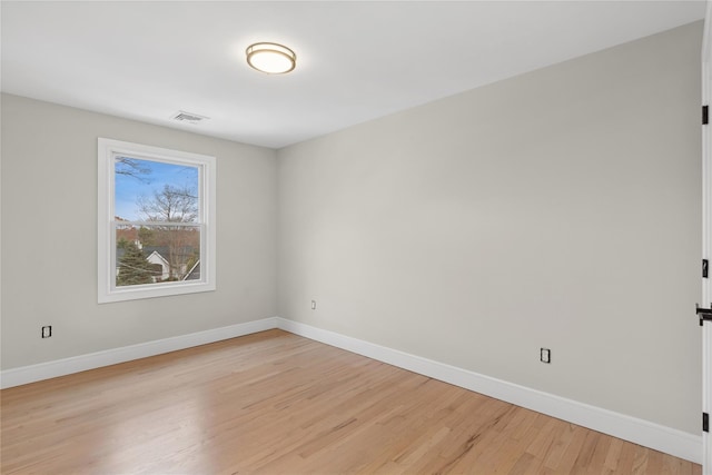 empty room featuring light wood-style floors, baseboards, and visible vents