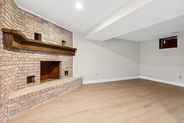 unfurnished living room featuring a brick fireplace, wood finished floors, and baseboards