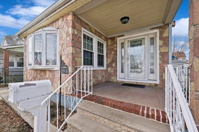 view of exterior entry featuring stone siding and a porch