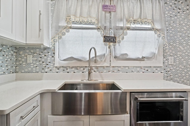 kitchen featuring tasteful backsplash, beverage cooler, light countertops, and white cabinetry