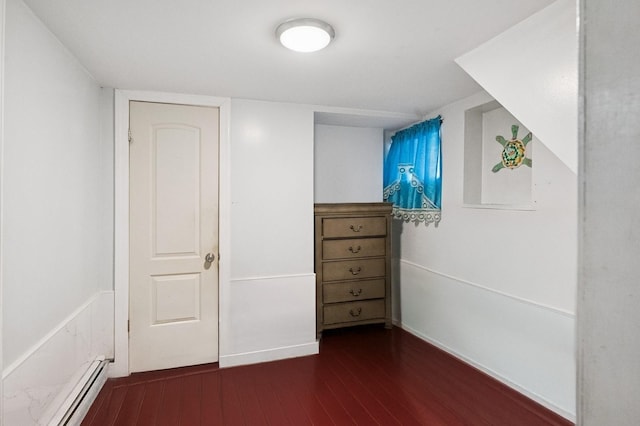 unfurnished bedroom with dark wood finished floors and baseboard heating