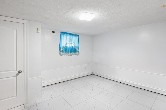 empty room with marble finish floor and a textured ceiling