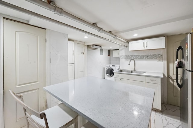 kitchen featuring a sink, white cabinetry, marble finish floor, freestanding refrigerator, and washer / clothes dryer