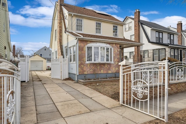 view of front of home with an outbuilding, a detached garage, fence, driveway, and a gate