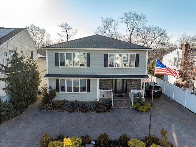 traditional-style house featuring covered porch, fence, and decorative driveway