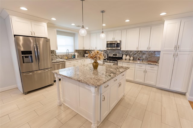 kitchen with a kitchen island, a sink, white cabinetry, appliances with stainless steel finishes, and decorative backsplash