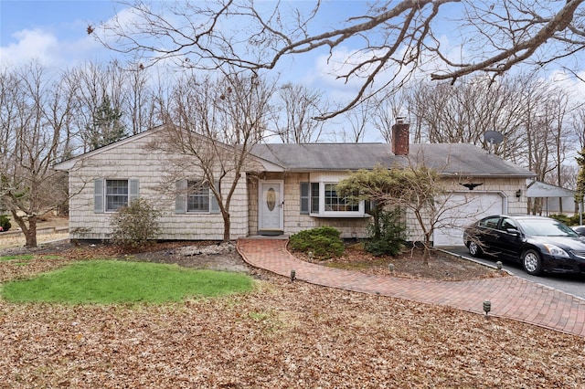 ranch-style house with a chimney, decorative driveway, a garage, and roof with shingles