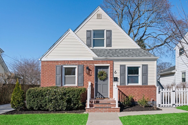 bungalow featuring fence, brick siding, and a shingled roof