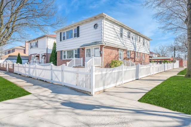 view of front facade featuring a fenced front yard, a residential view, and brick siding