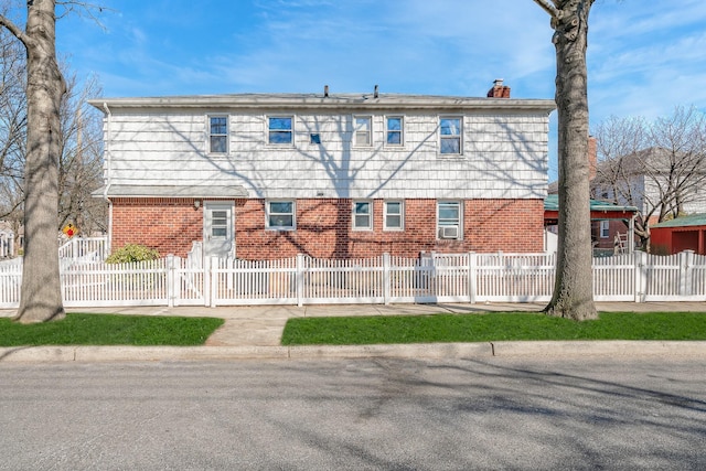 rear view of house with a fenced front yard, brick siding, and a chimney