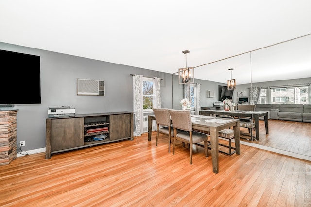 dining space with light wood-style flooring, a notable chandelier, baseboards, and a wealth of natural light