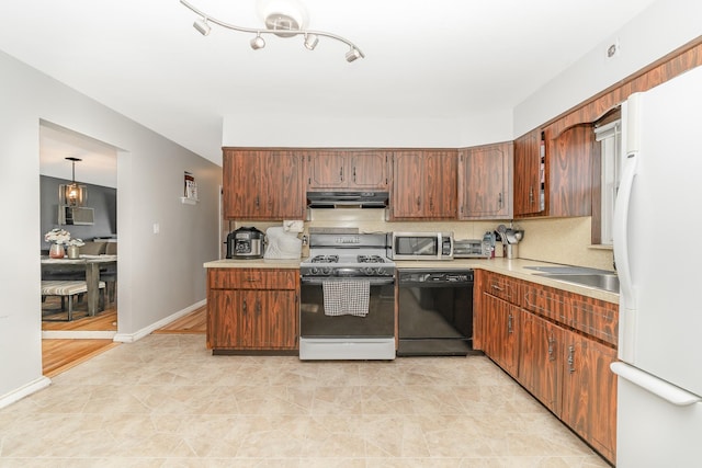 kitchen featuring under cabinet range hood, stainless steel microwave, freestanding refrigerator, gas stove, and dishwasher