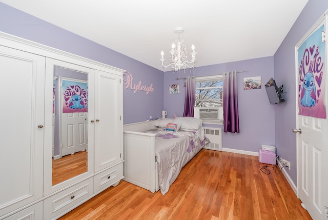 bedroom with cooling unit, baseboards, light wood-style flooring, radiator heating unit, and a chandelier