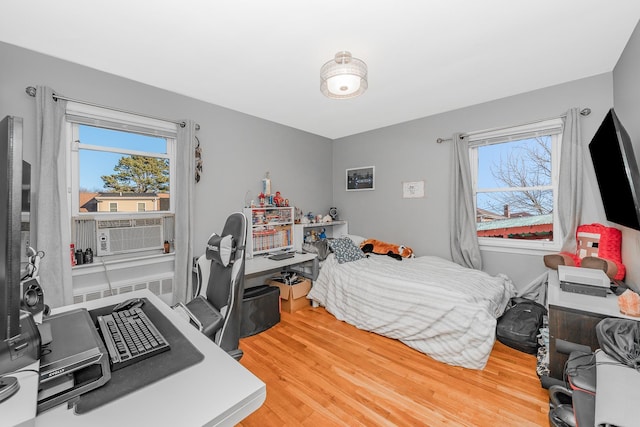 bedroom with multiple windows, wood finished floors, and cooling unit