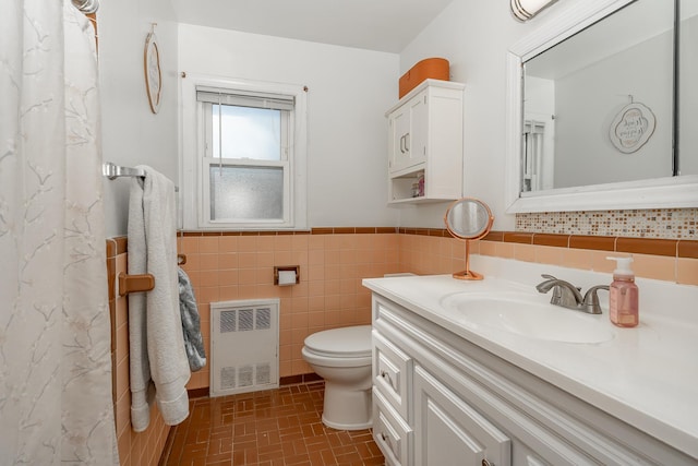 full bathroom with toilet, radiator, tile walls, wainscoting, and vanity