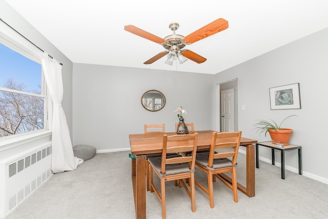 dining space featuring light carpet, ceiling fan, radiator, and baseboards