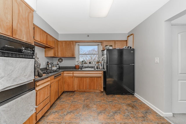 kitchen with dark countertops, black appliances, baseboards, and a sink