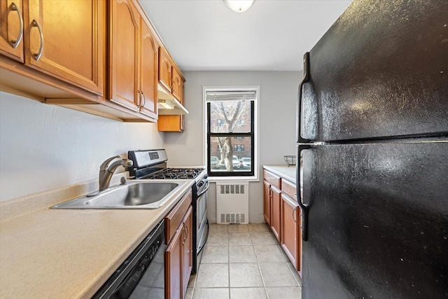 kitchen with light tile patterned floors, radiator heating unit, light countertops, black appliances, and a sink