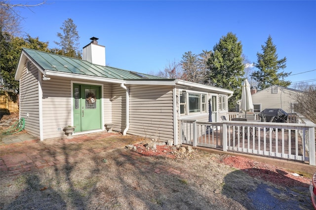 view of front of house featuring a standing seam roof, a chimney, and metal roof