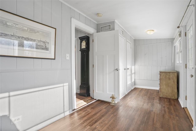 interior space featuring visible vents, ornamental molding, a decorative wall, and wood finished floors