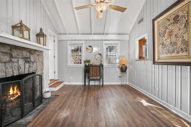 living area with a ceiling fan, wood finished floors, baseboards, lofted ceiling with beams, and a fireplace