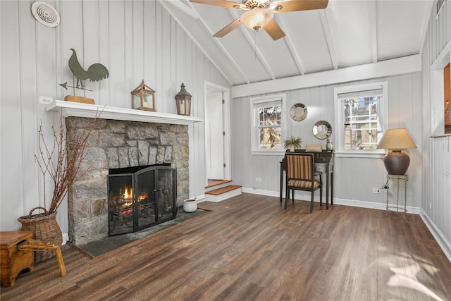 living room featuring vaulted ceiling with beams, ceiling fan, baseboards, a fireplace, and wood finished floors