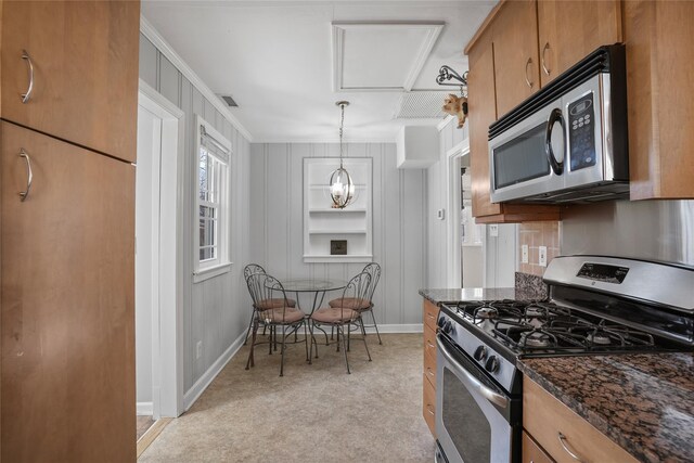 kitchen with visible vents, built in shelves, brown cabinets, dark stone countertops, and appliances with stainless steel finishes