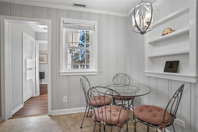 dining space with visible vents, built in shelves, ornamental molding, an inviting chandelier, and baseboards