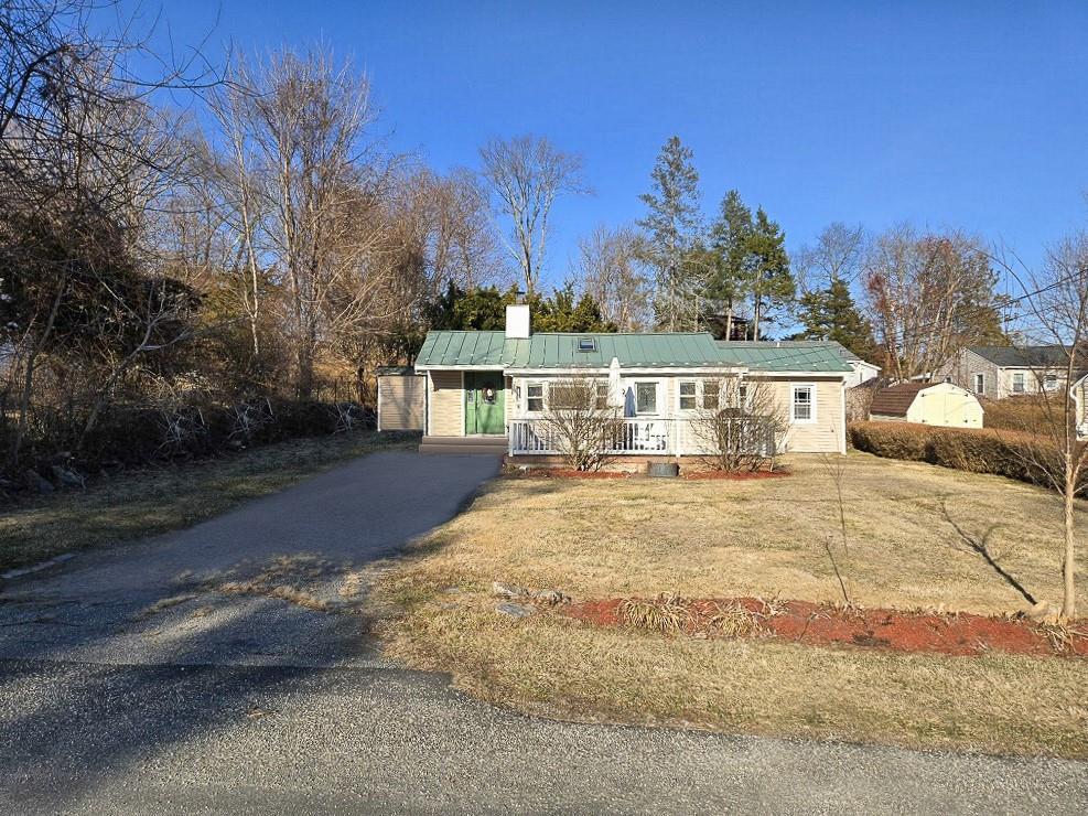 single story home featuring a porch, driveway, metal roof, and a front lawn