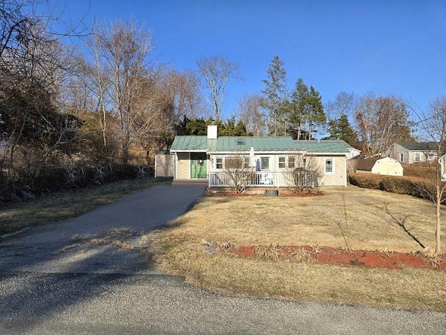 single story home featuring a porch, driveway, metal roof, and a front lawn