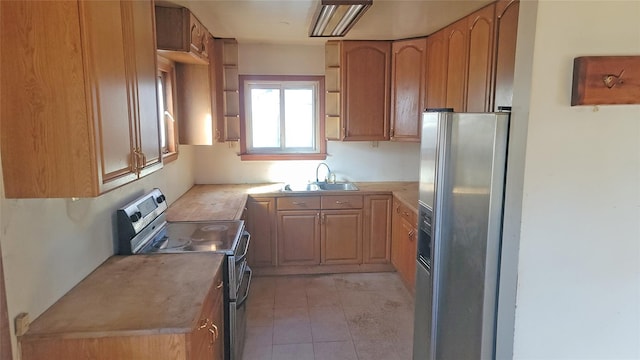 kitchen with light tile patterned floors, stainless steel appliances, a sink, and light countertops